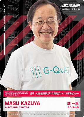 産総研（国立研究開発法人産業技術総合研究所）の研究者カード。白いG-QuAT Tシャツを着て微笑む益一哉氏の写真が掲載され、氏名「益 一哉（MASU KAZUYA）」と、量子・AI融合技術ビジネス開発グローバル研究センター（G-QuAT）のセンター長であることが表示されている。