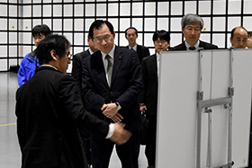 スマートシステム研究棟電波暗室で説明をお聞きになる浜田復興副大臣(中央)の写真
